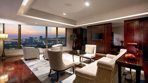 Una sala moderna con vista a la ciudad, una mesa de centro redonda y asientos cómodos.