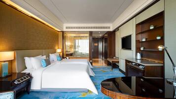 Habitación de hotel con una cama grande, un escritorio, un televisor y un mini bar.