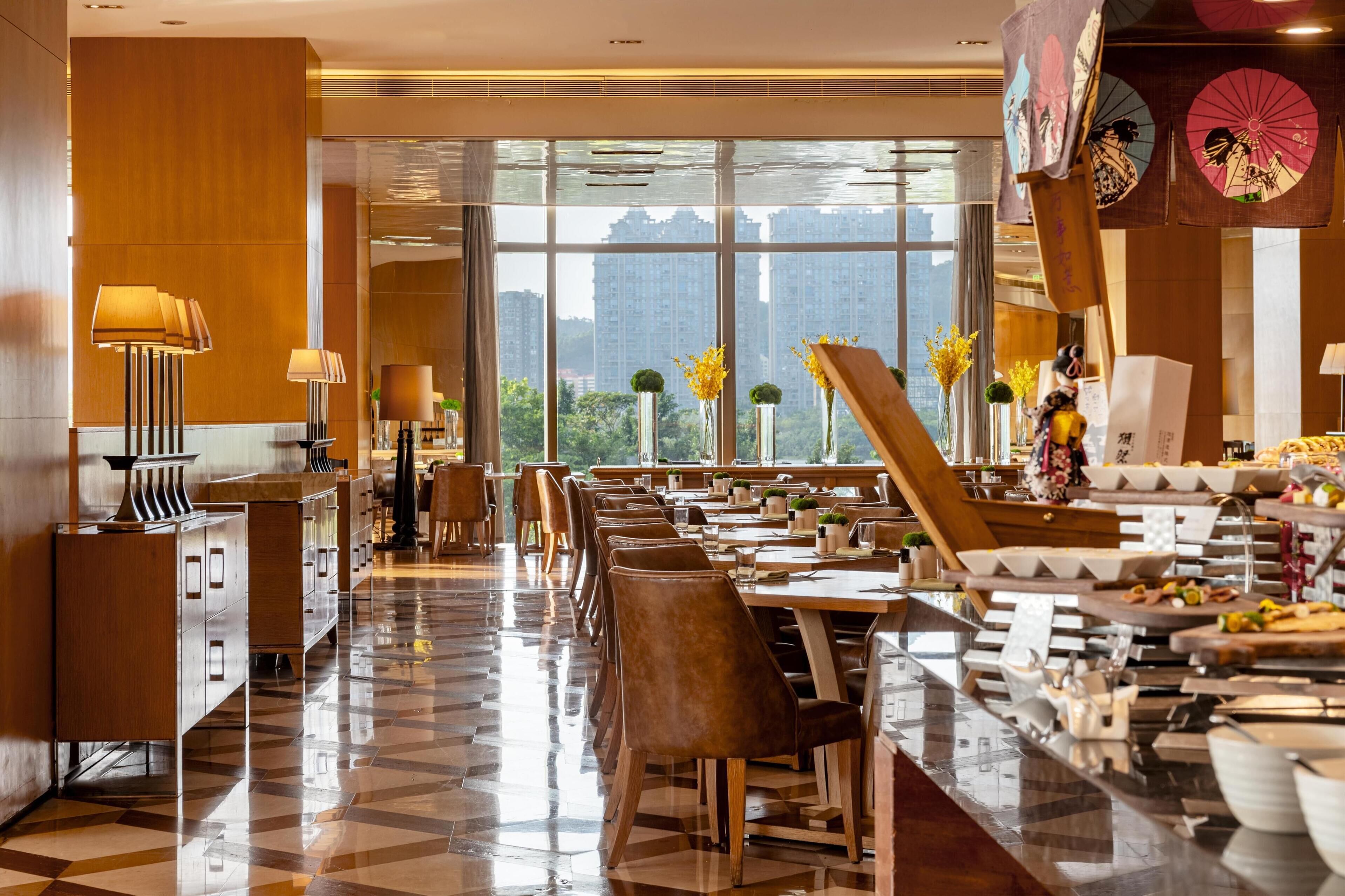 A modern hotel lobby with a checkered floor, wooden furniture, and large windows offering a city view.
