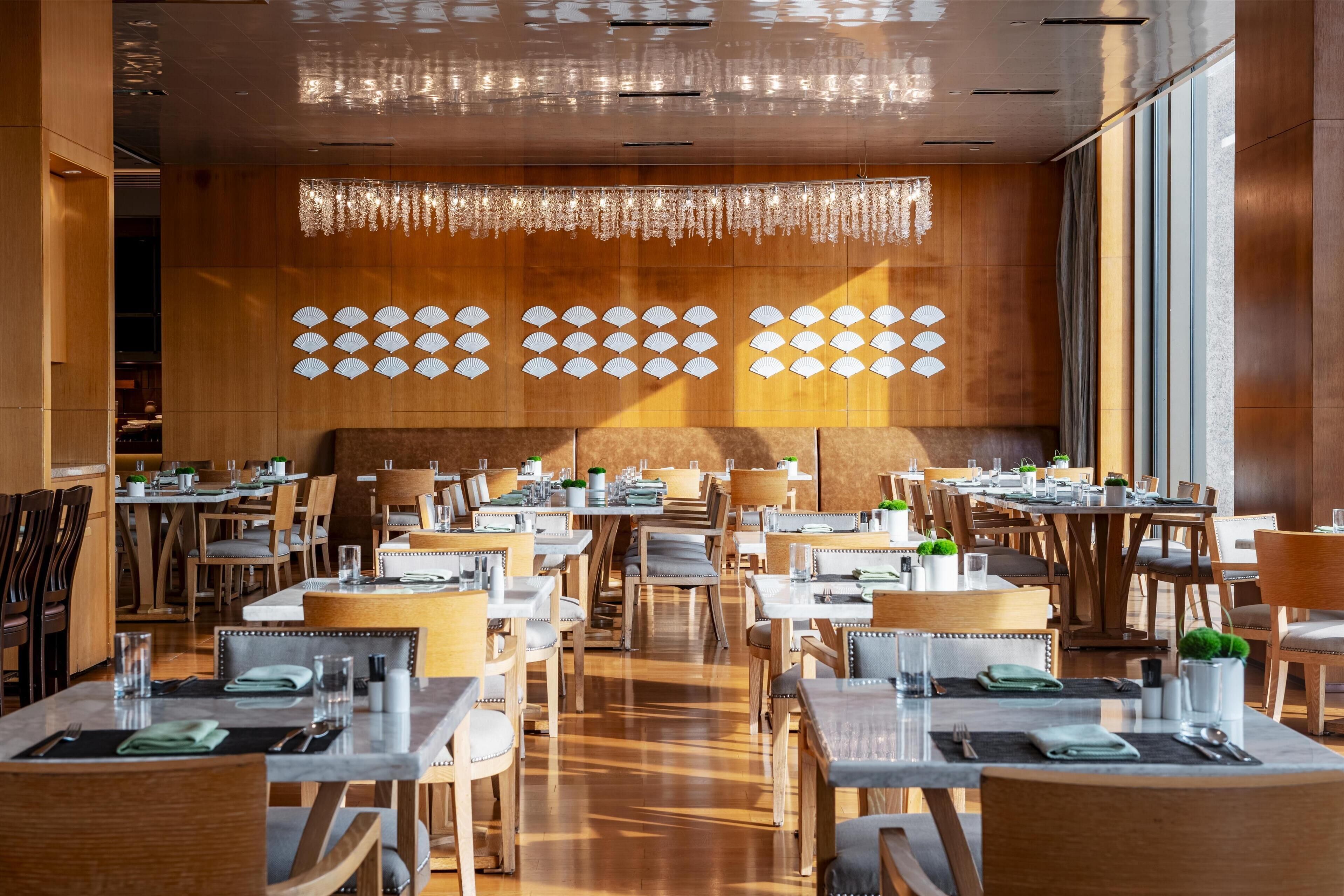 A modern restaurant with wooden walls, large windows, and neatly arranged tables and chairs.