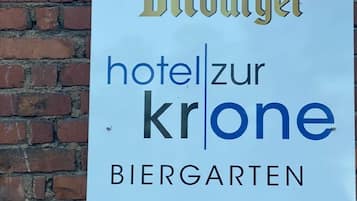 Señal de un hotel llamado "hotel zur krone", con jardín de cerveza y una flecha apuntando a la derecha.