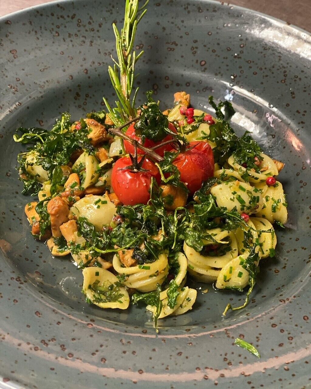 Een bord eten met pasta, tomaten en groenten.