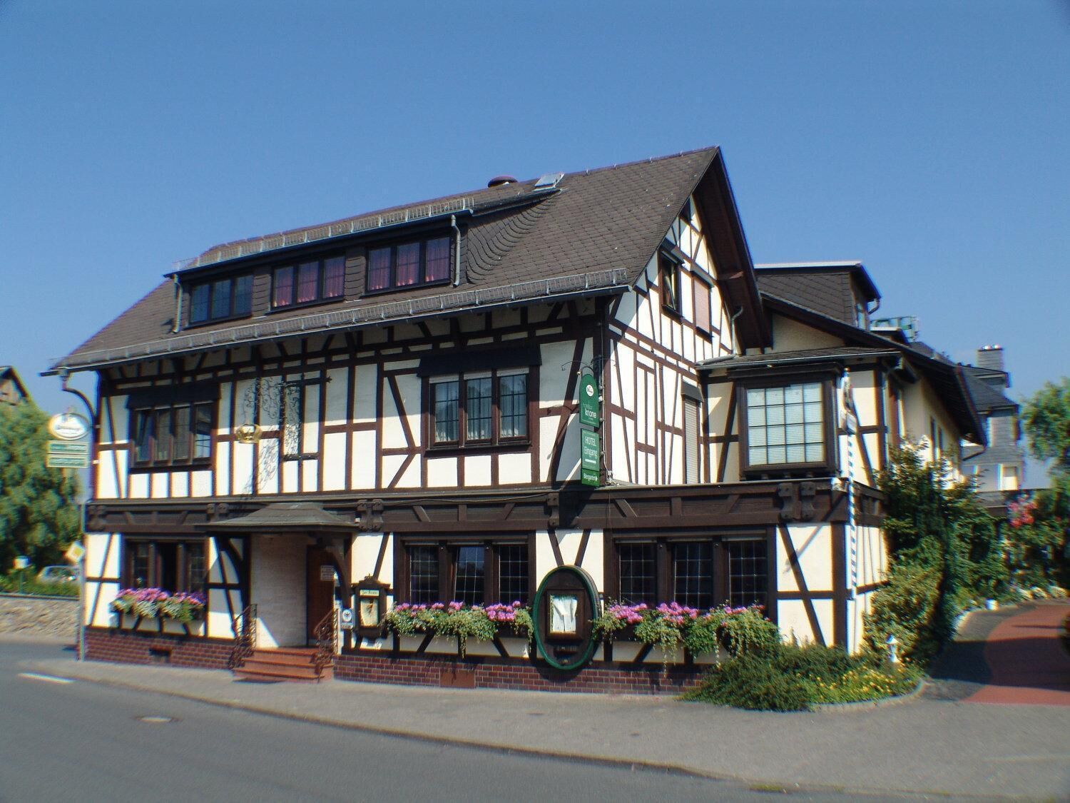 A traditional half-timbered building with a prominent green sign indicating it is a hotel.