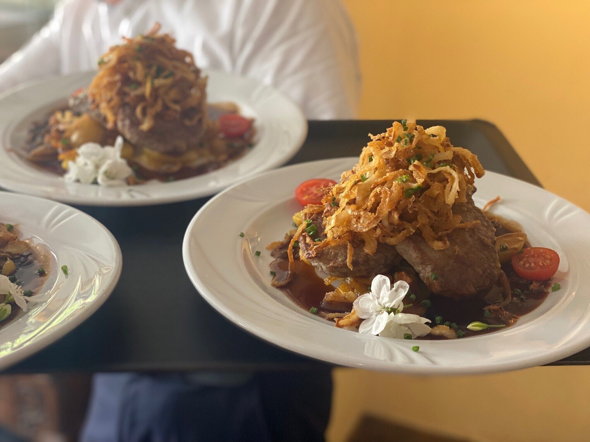 Una mesa con platos de comida, incluyendo un guiso de carne y cebolla, y un postre con cereza.