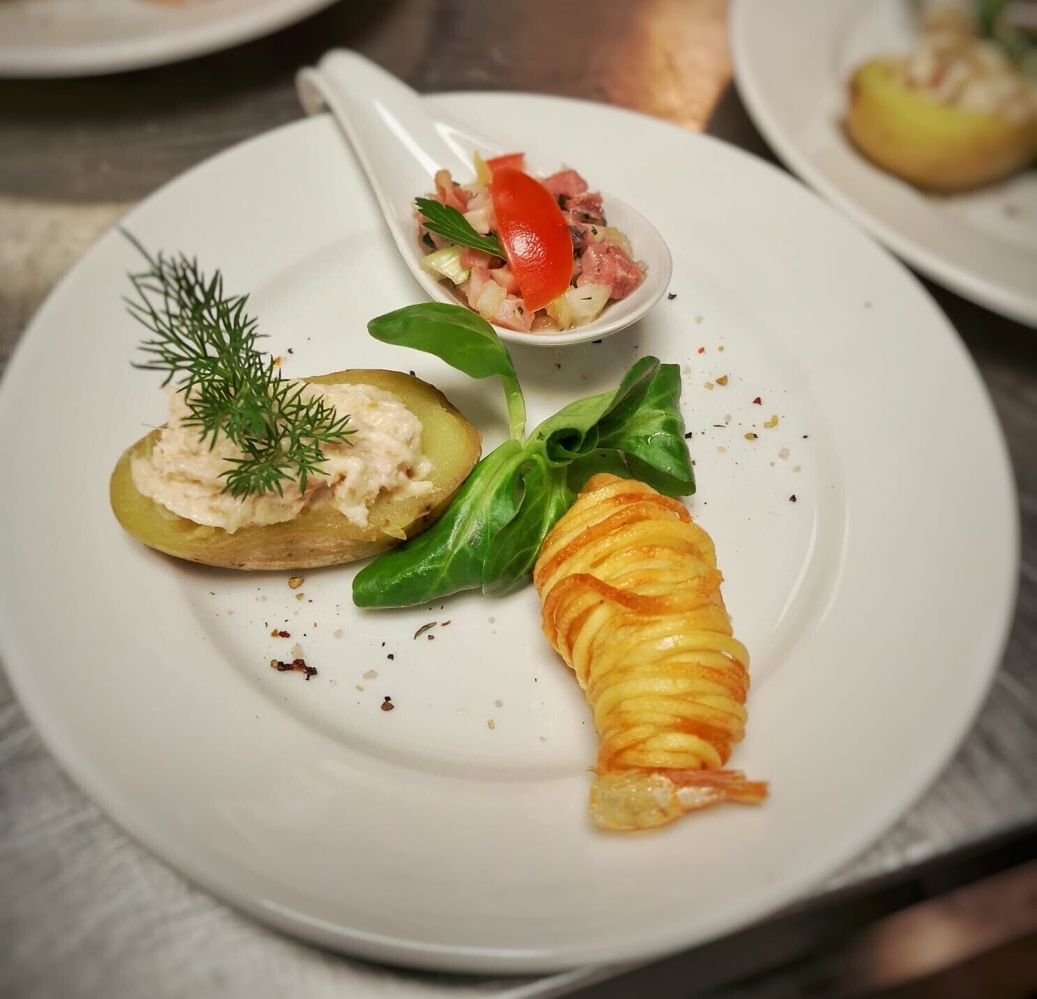 A plate with a stuffed potato, a rolled apple, and a small bowl of salad.