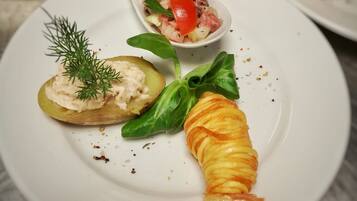 A plate with a stuffed potato, a rolled apple, and a small bowl of salad.