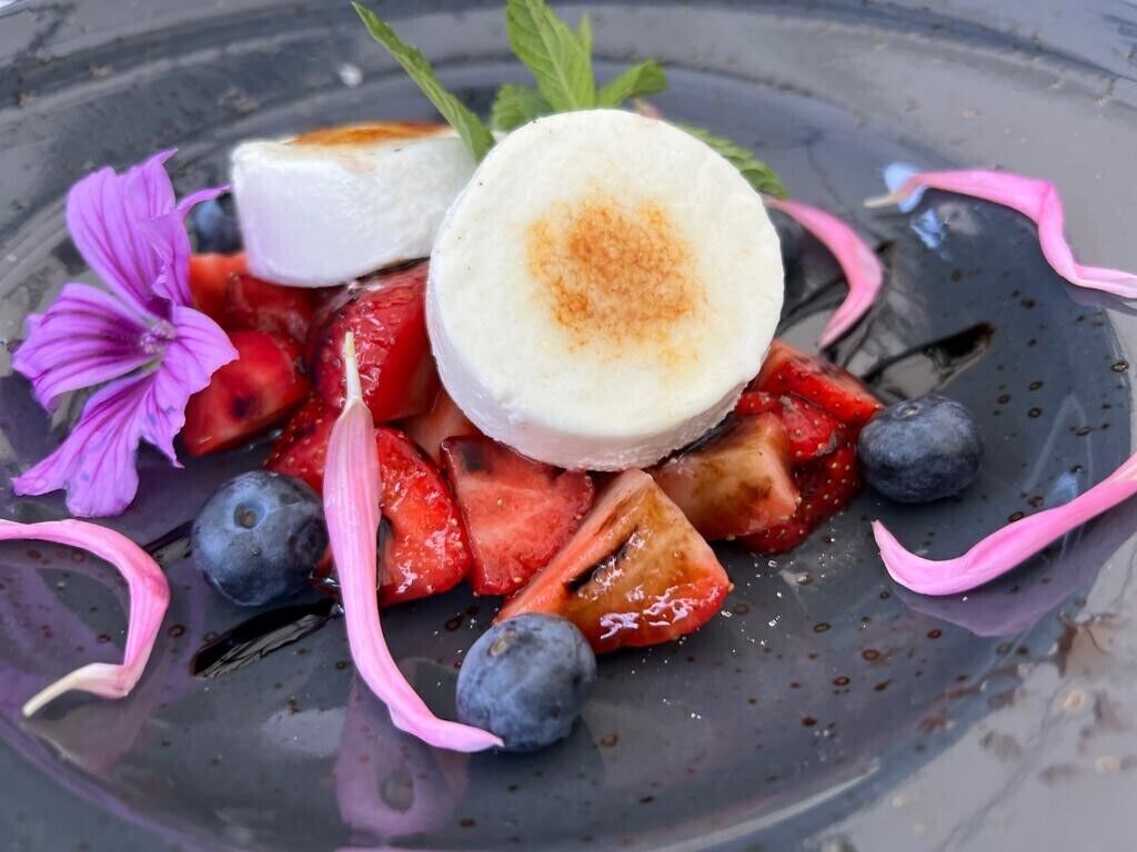 Une assiette de dessert avec des fraises, des myrtilles et une guimauve.