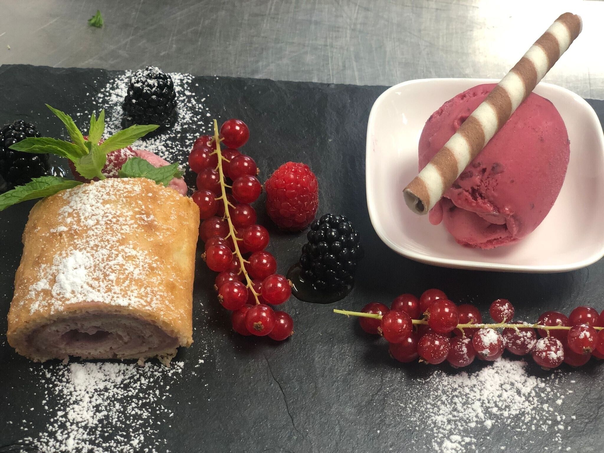 Un postre con bayas y un hojaldre sobre una tabla de piedra.