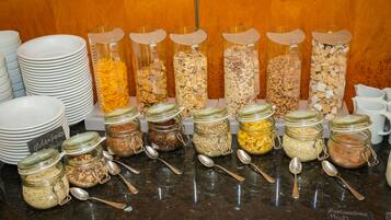 A breakfast buffet with various food options in jars and plates.