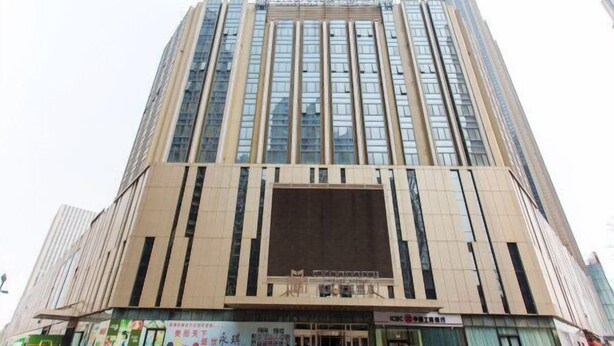 A tall, modern building with a large entrance and a prominent billboard at the ground level.