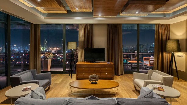 A modern living room with a large TV, comfortable seating, a coffee table, and a city view. - Radisson Blu Hotel Istanbul Asia (Istanbul)