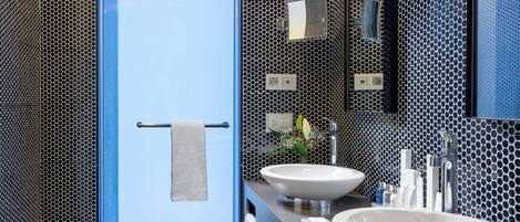 A modern bathroom with a large mirror, two sinks, and a shower area.