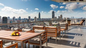 A rooftop terrace with wooden furniture, a table with fruit, and a city skyline view. - Radisson Blu Hotel Istanbul Asia (Istanbul)