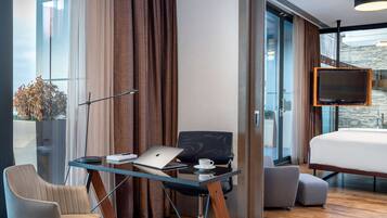 Una habitación de hotel moderna con una cama grande, un escritorio con una computadora portátil, una silla y un televisor.