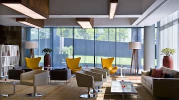 A modern lounge area with multiple seating options, large windows, and contemporary lighting fixtures.