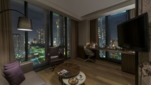 A modern hotel room with a large window offering a city view, a comfortable sofa, a coffee table, a desk with a chair, and a flat-screen TV. - Radisson Blu Hotel Istanbul Asia (Istanbul)