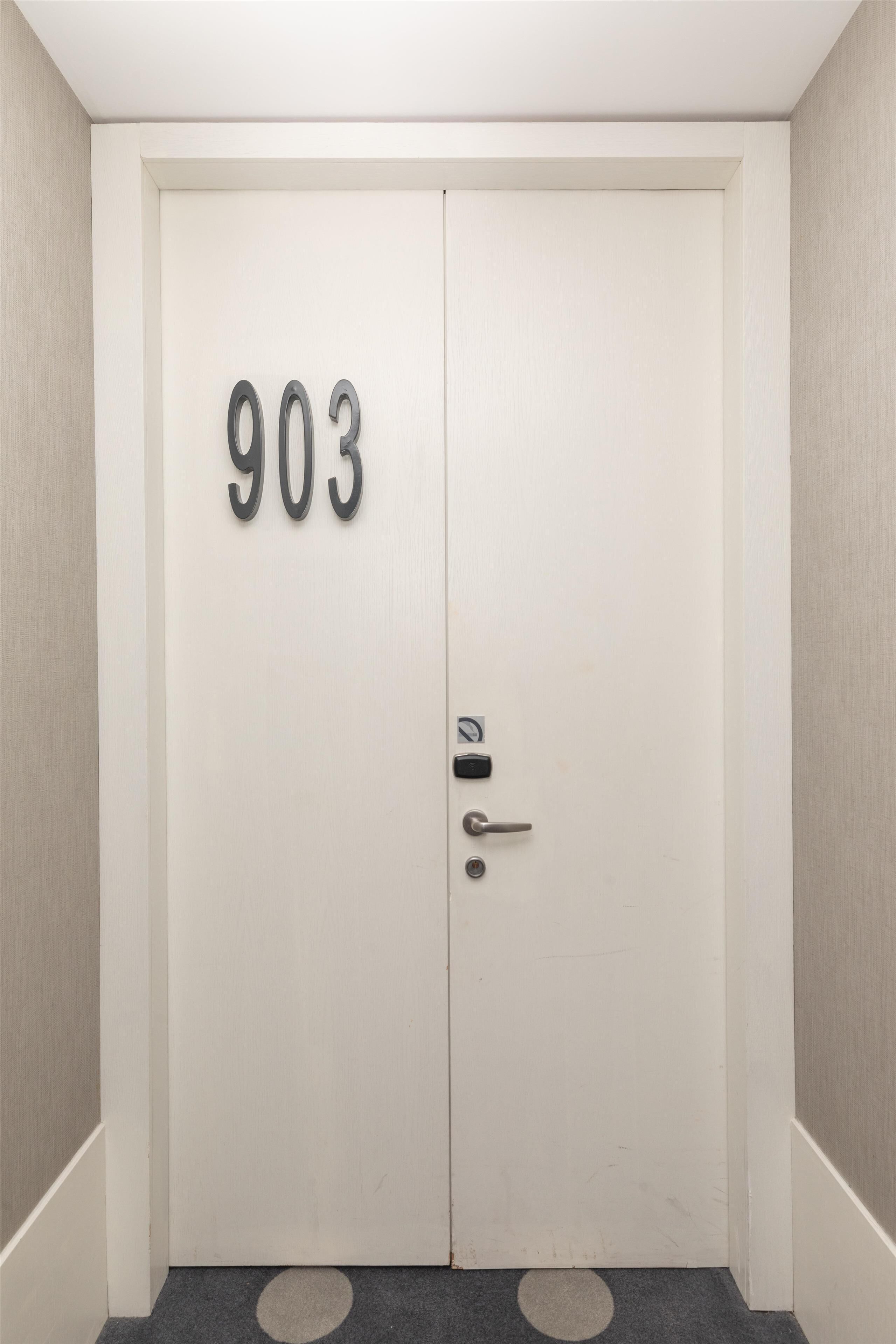 A white door with the number 903 on it, a keyhole, and a doorknob.