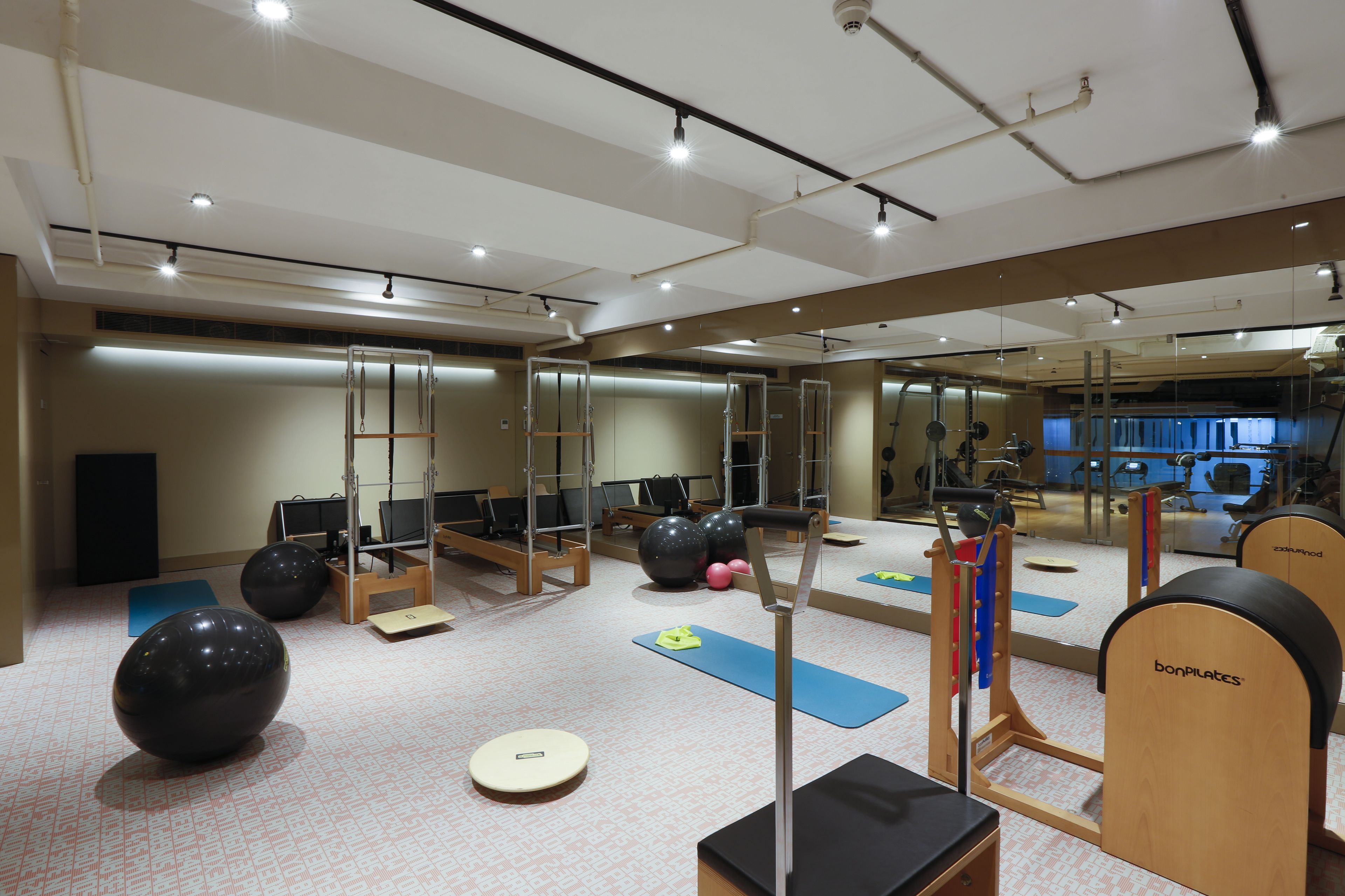 A gym with exercise equipment, mirrors, and yoga mats.
