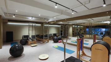 A gym with exercise equipment, mirrors, and yoga mats.