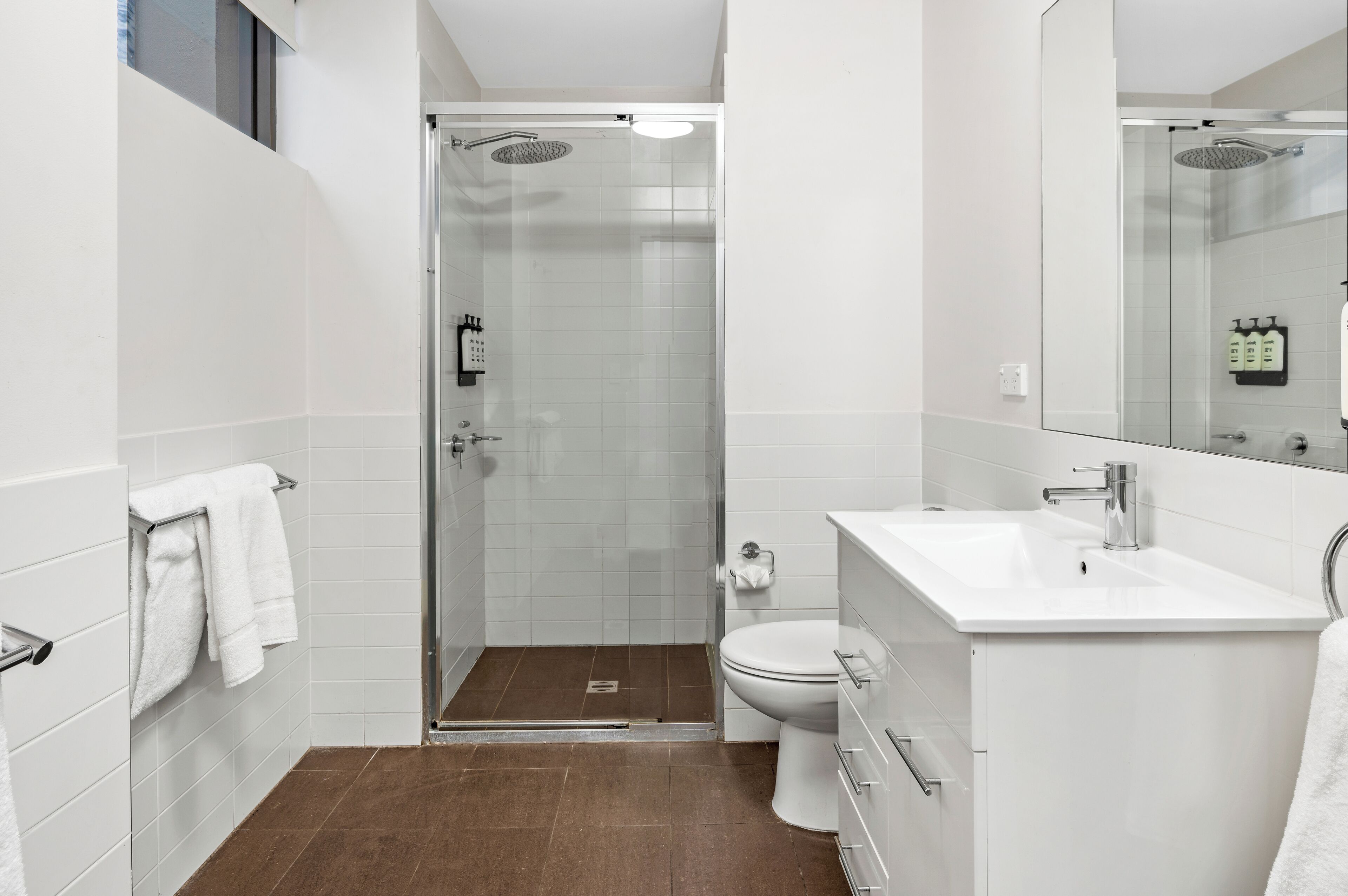 A modern bathroom with a glass-enclosed shower, a white sink, and a toilet.