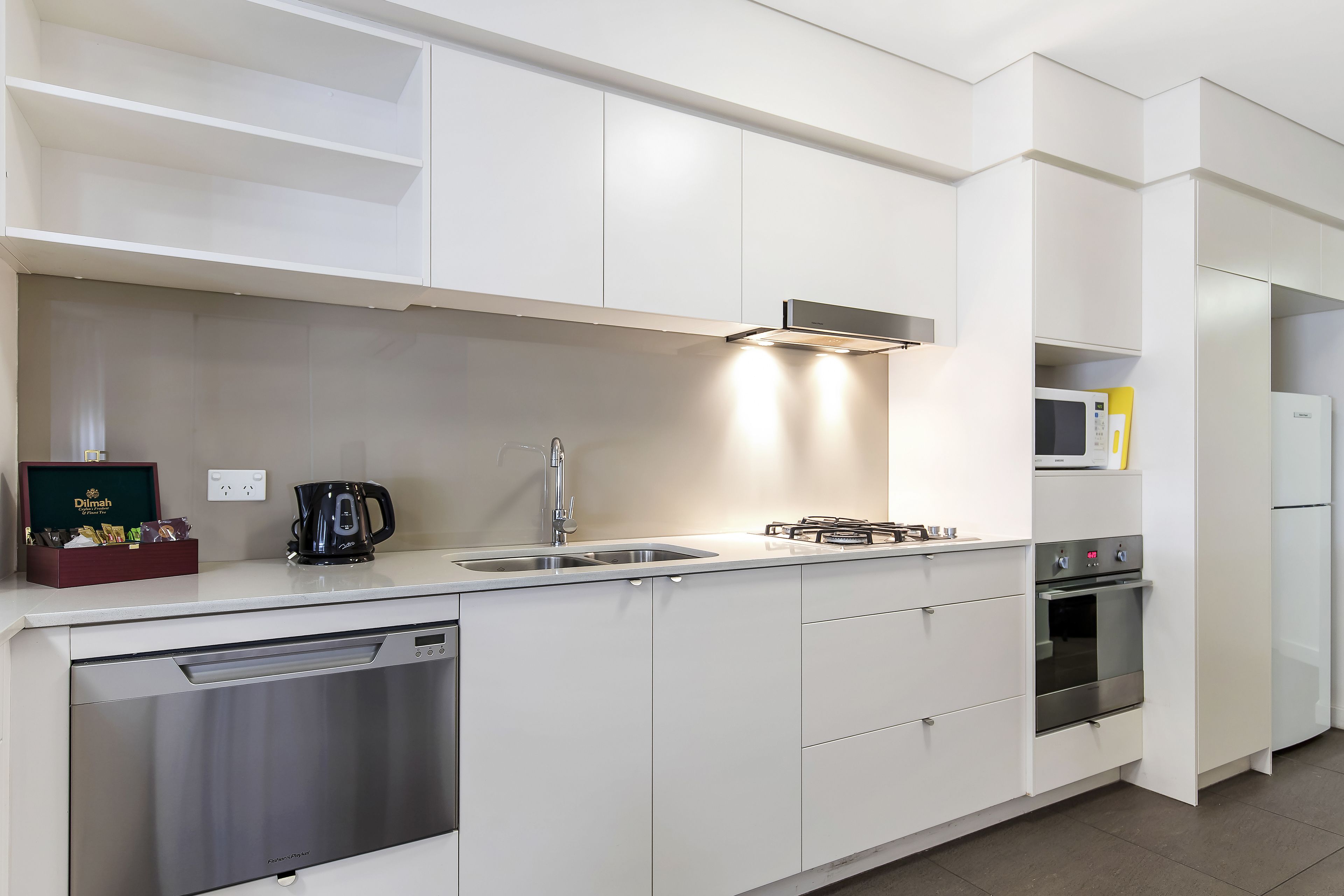 A modern kitchen with white cabinetry, a dishwasher, a stove, and a microwave.