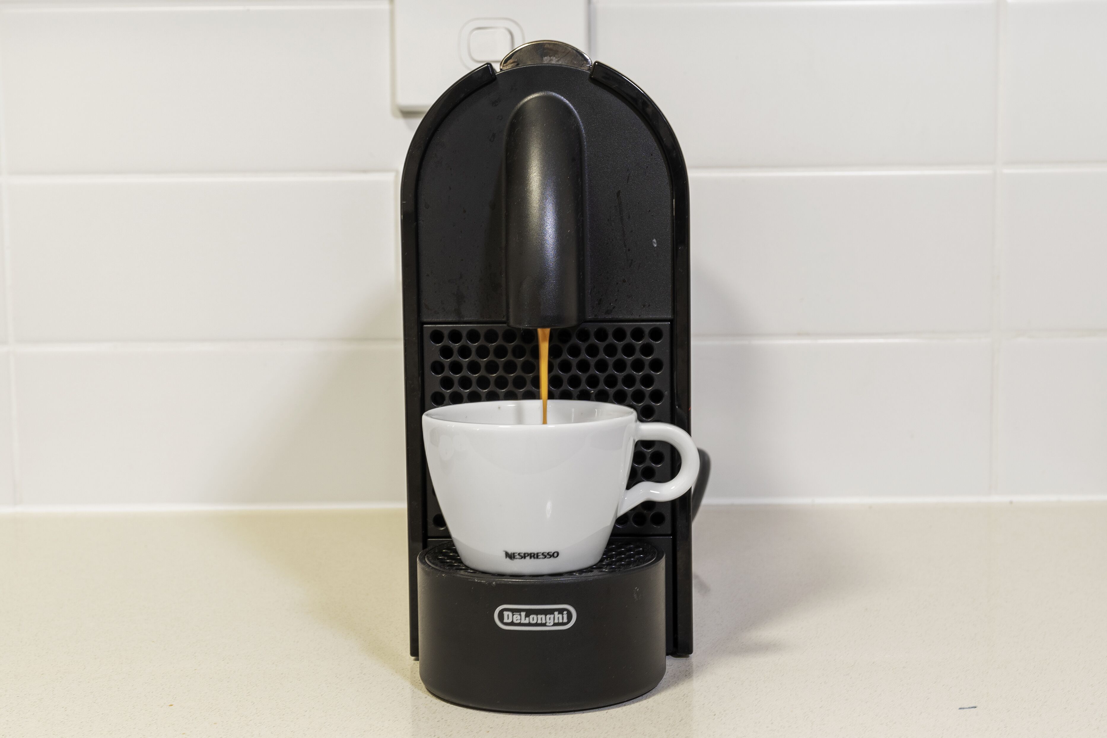 A Nespresso coffee machine with a white cup on its base.