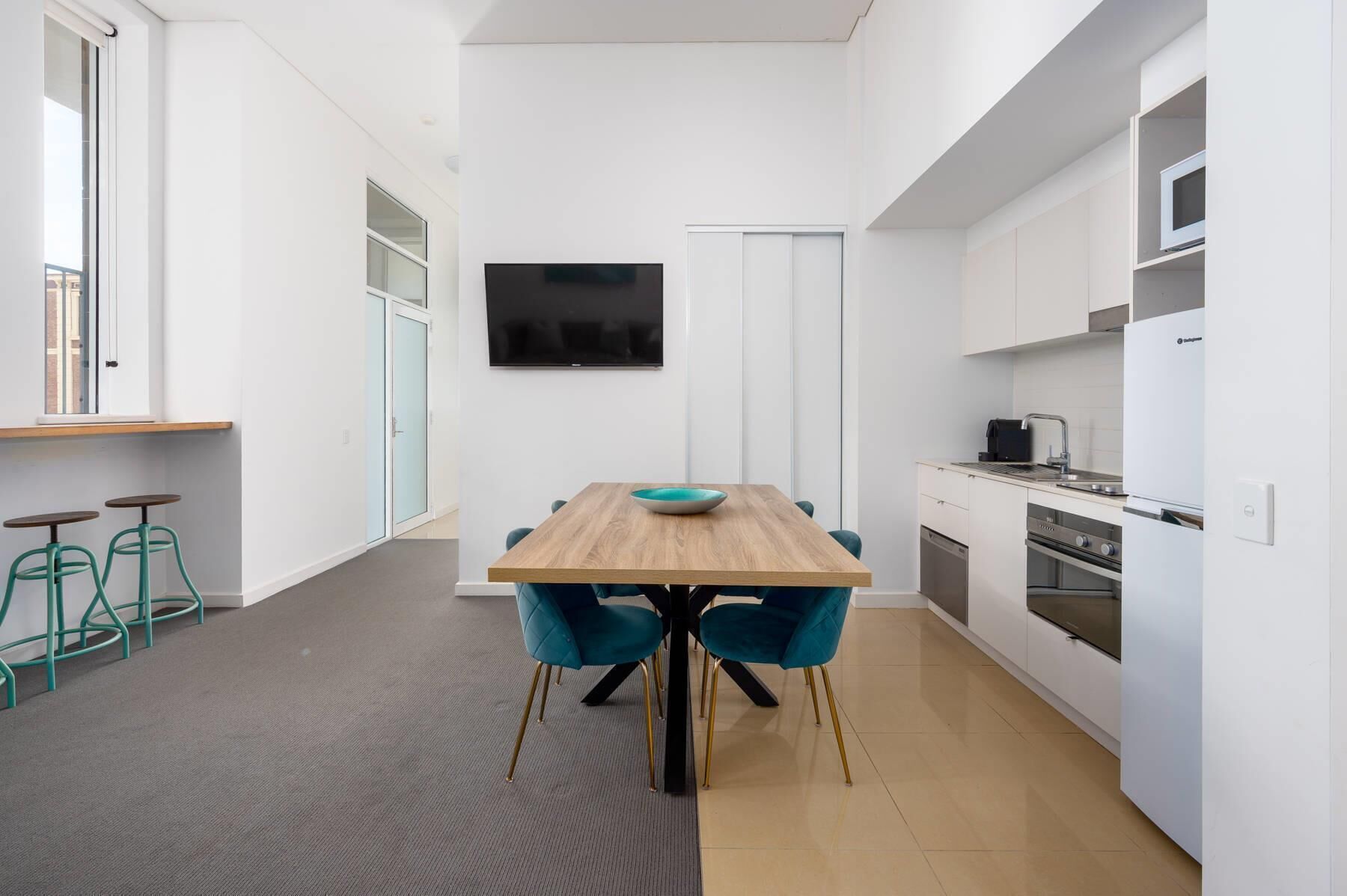 Une cuisine moderne avec un coin repas, un téléviseur à écran plat et une vue sur l’extérieur.
