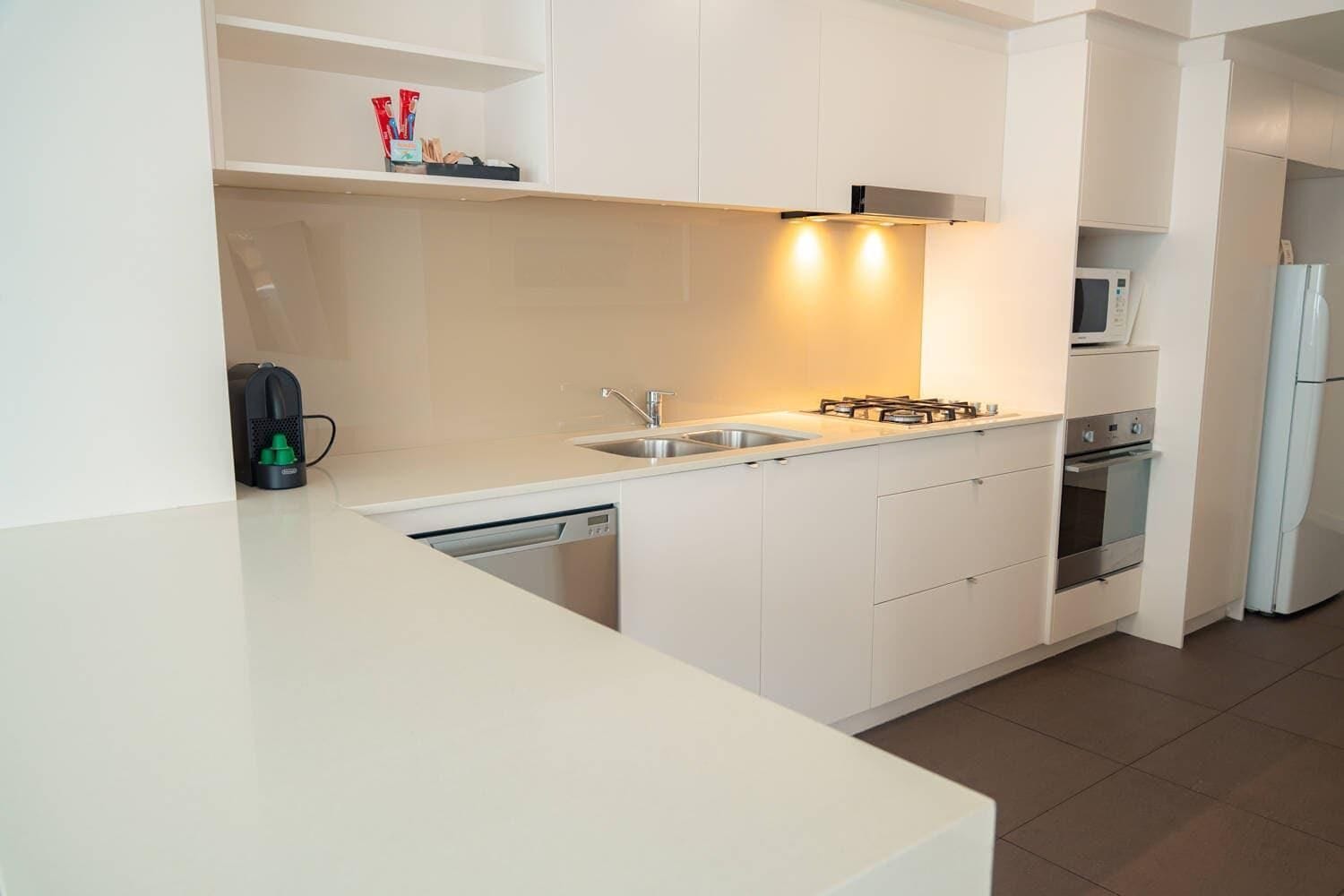 A modern kitchen with a dishwasher, sink, stove, and microwave.