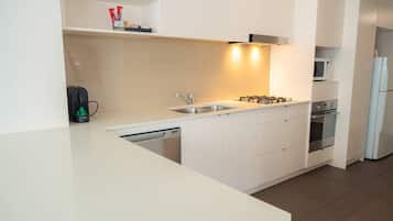 A modern kitchen with a dishwasher, sink, stove, and microwave.