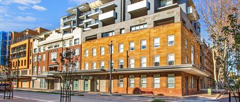 A multi-story hotel with balconies, a covered entrance, and a street view.