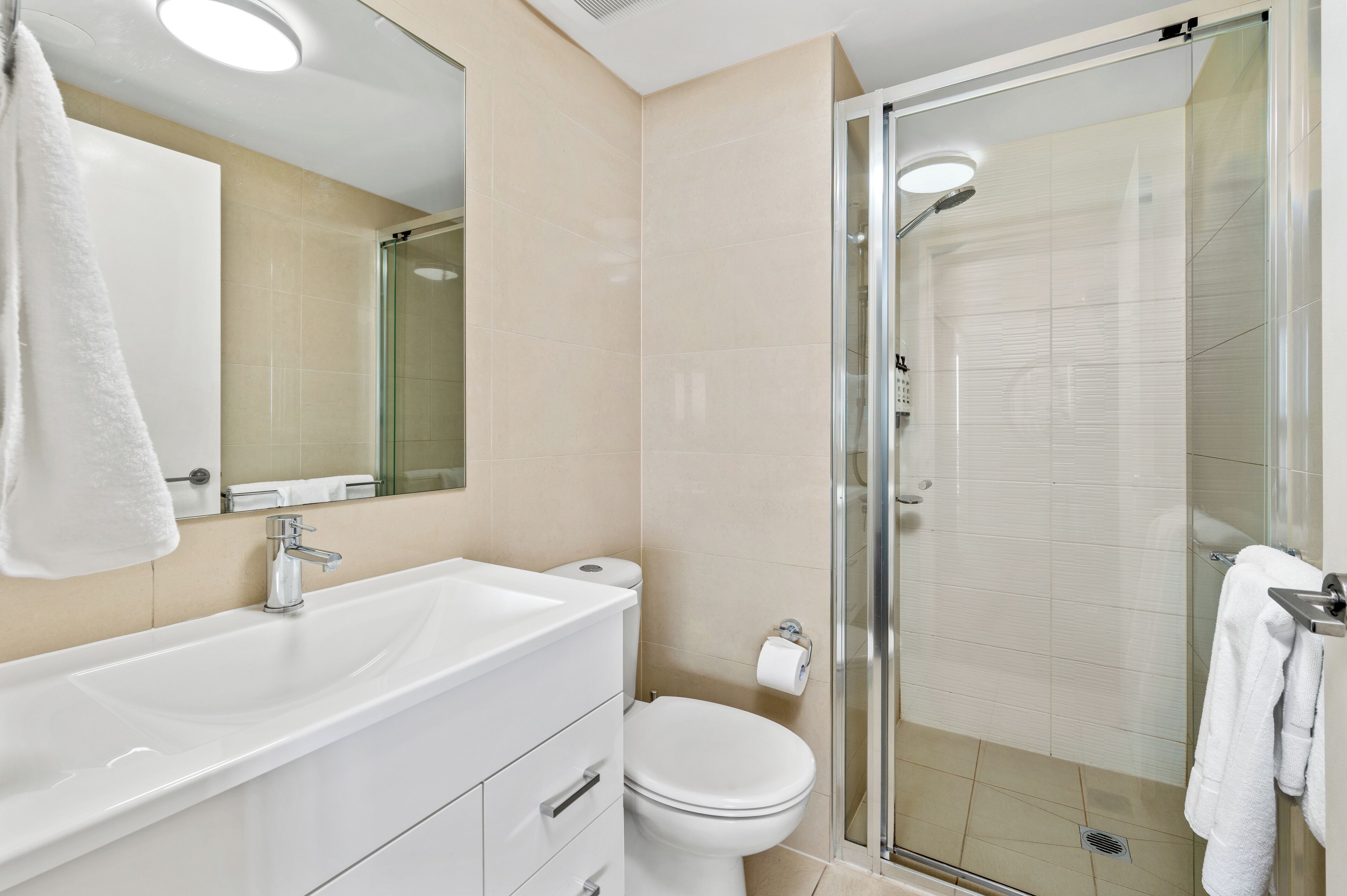 A modern bathroom with a glass-enclosed shower, a white sink, and a toilet.