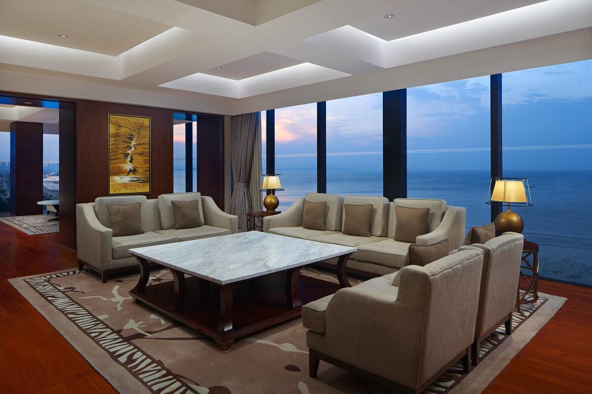 A spacious living room with a large sofa set, a coffee table, and a view of the ocean.