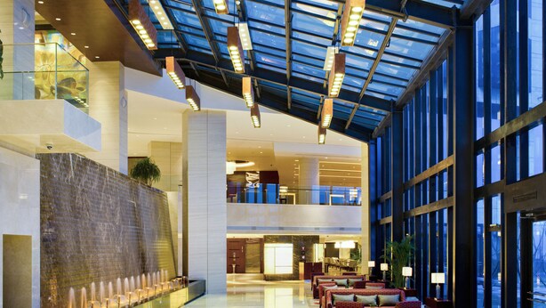A spacious lobby with a water feature, seating area, and large windows. - Sheraton Yantai Golden Beach Resort (Yantai)