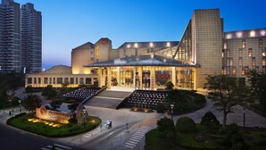 A hotel with a modern architectural design, featuring a prominent entrance and a well-maintained garden area. - Sheraton Yantai Golden Beach Resort (Yantai)