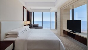 A hotel room with a large bed, a TV, and a view of the sea. - Sheraton Yantai Golden Beach Resort (Yantai)