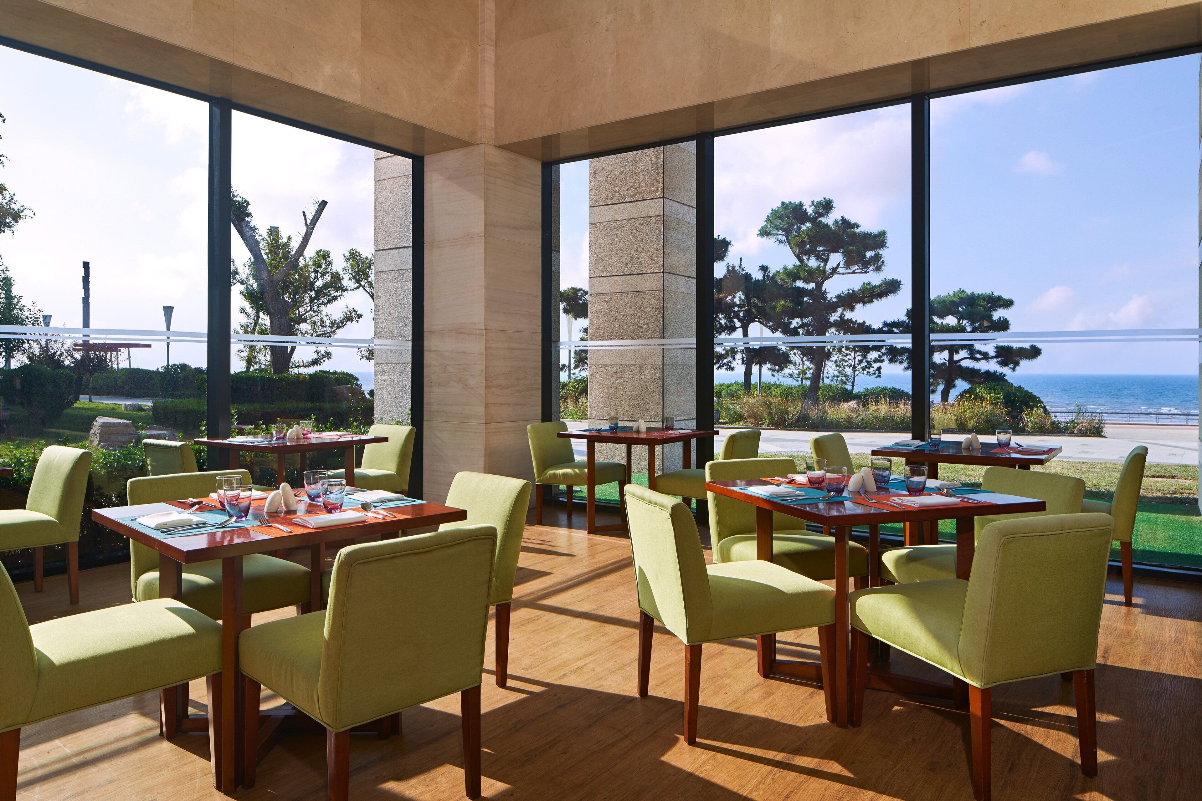 Un restaurant doté d’une terrasse, de grandes fenêtres et offrant une vue sur la mer.