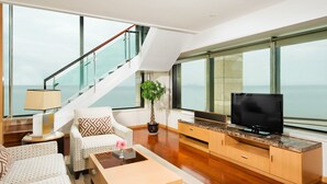 A modern living room with a staircase, a television, and a view of the sea. - Sheraton Yantai Golden Beach Resort (Yantai)