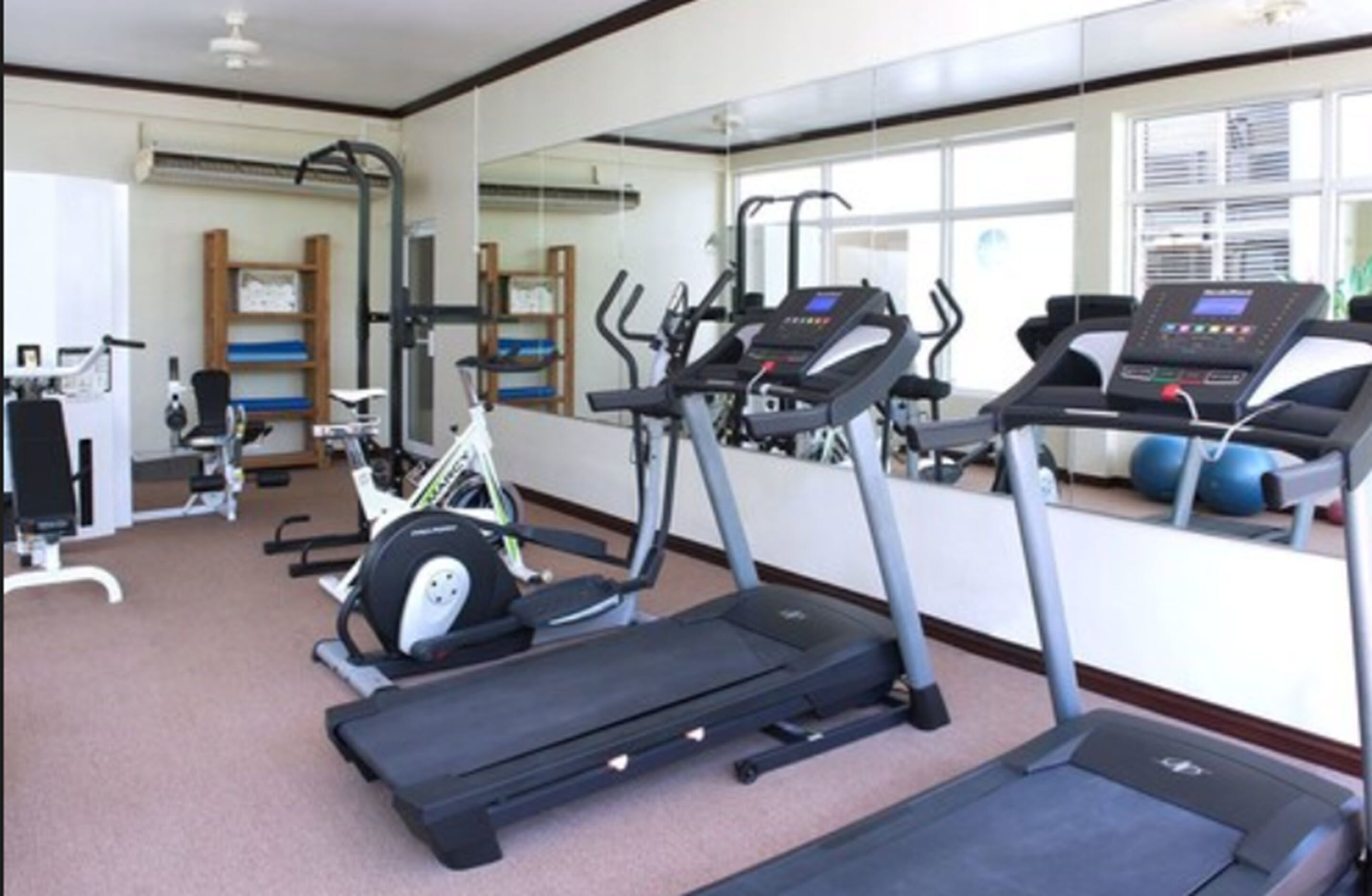 Une salle de sport équipée de tapis de course, de vélos elliptiques et de matériel de musculation.