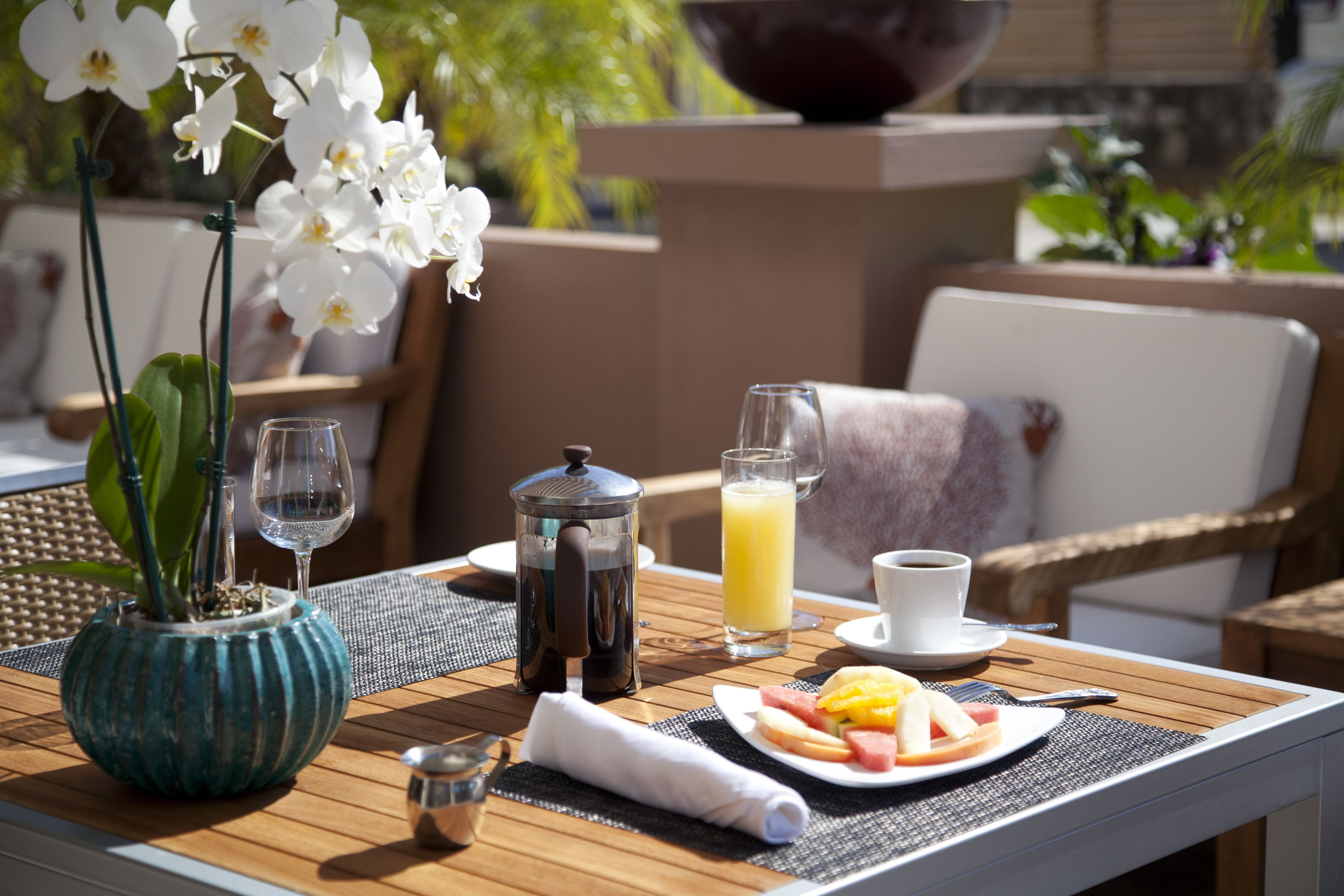Ein Frühstückstisch mit Kaffeekanne, Orangensaftglas, Kaffeetasse und Obstteller.