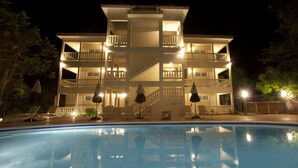 Un hotel de varios pisos con una piscina al frente.