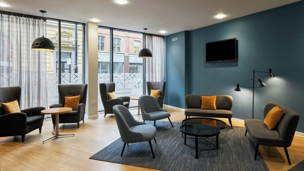 A modern lounge area with sofas and armchairs, a coffee table, and a TV mounted on the wall. - Four Points Flex by Sheraton Newcastle (Newcastle-upon-Tyne)