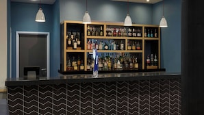 A bar area with a black and white patterned wall, wooden shelves with liquor bottles, and pendant lights. - Four Points Flex by Sheraton Newcastle (Newcastle-upon-Tyne)