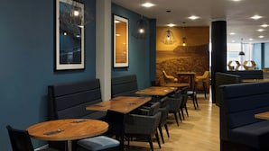 A modern restaurant interior with wooden tables and black upholstered booths, framed artwork on the walls, and pendant lighting. - Four Points Flex by Sheraton Newcastle (Newcastle-upon-Tyne)