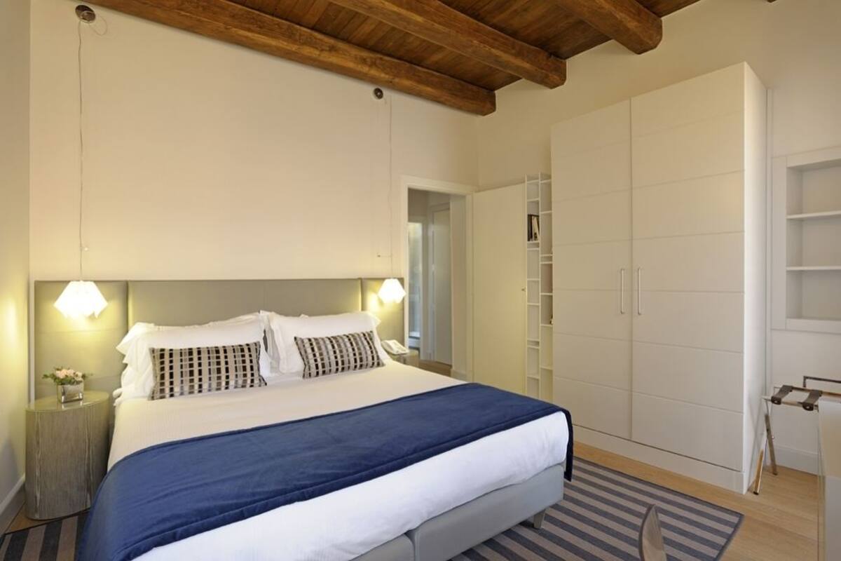 Una camera da letto con un letto grande, lampade sui comodini, un armadio e una trave in legno al soffitto.