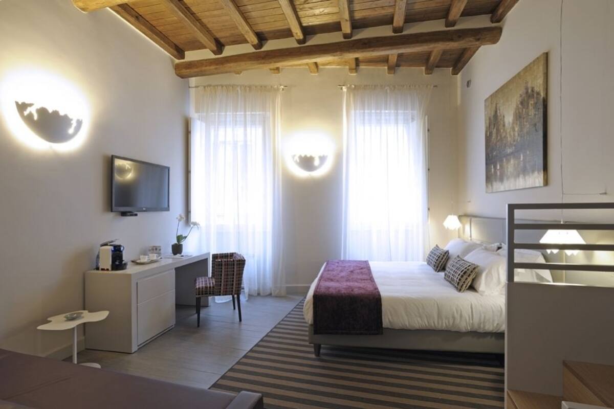 Una moderna camera d'albergo con un letto, una scrivania, una sedia e una televisione.