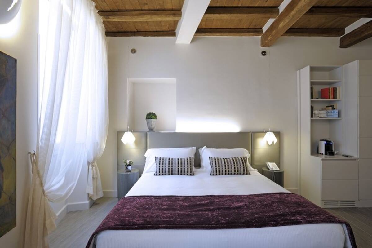 Camera d'albergo con un letto, lampade da comodino, un tavolino, un comodino e un armadio a muro.