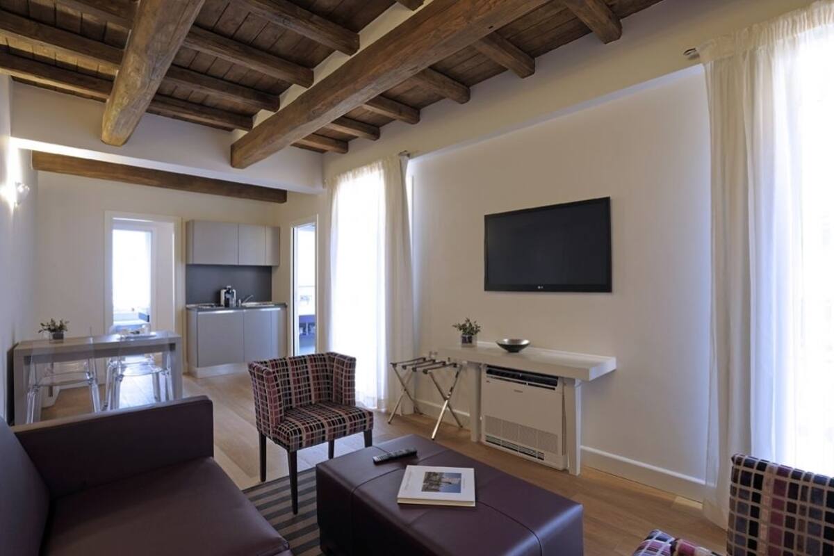 Un soggiorno moderno con un divano, un tavolo da pranzo e una zona cucina sullo sfondo.