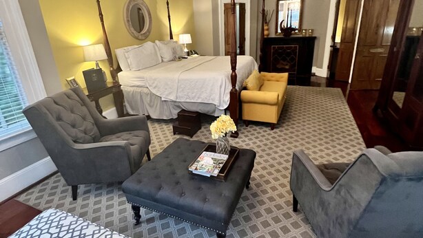 A spacious living room with a large bed, a chandelier, and a fireplace. - Barksdale House Inn (Charleston)