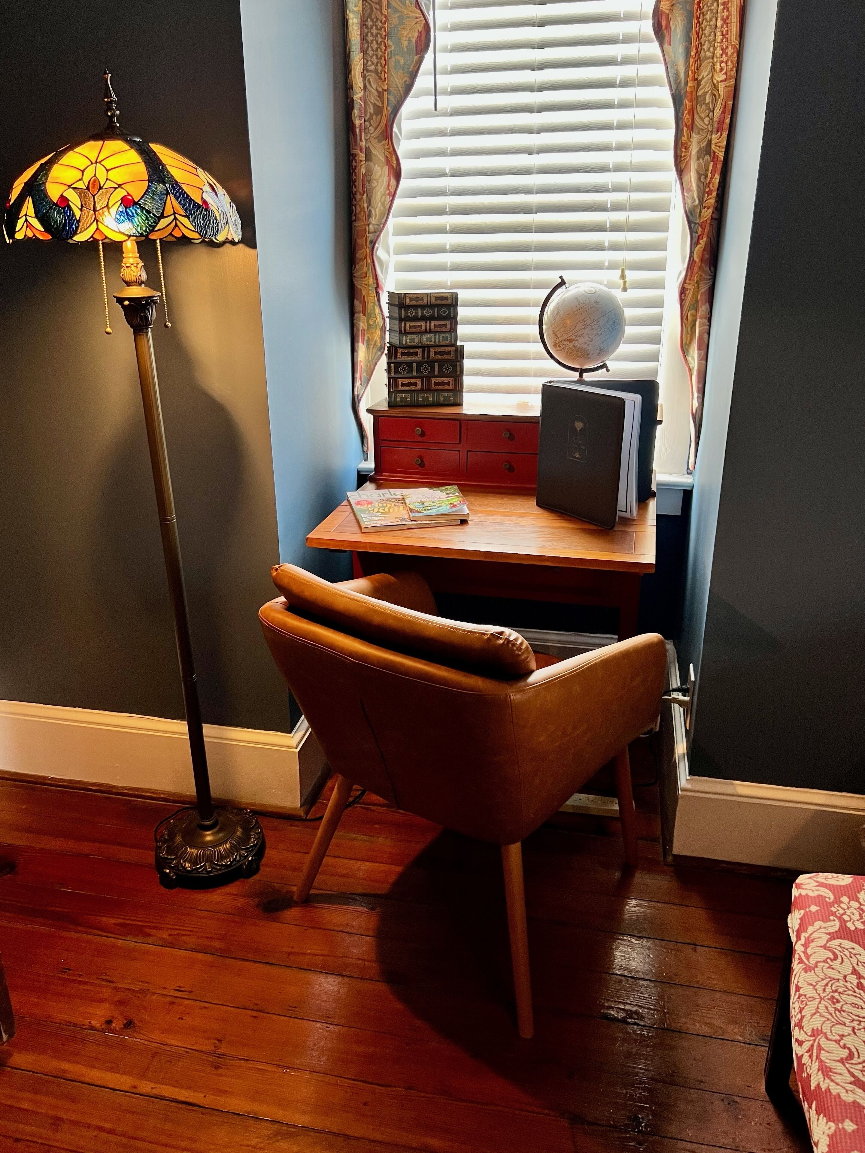 A study area with a desk, chair, globe, books, and a lamp.