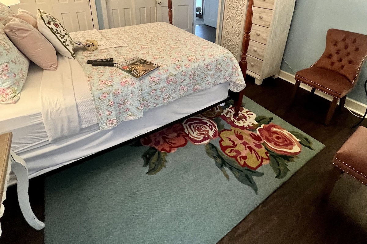 Una camera da letto con un letto, una cassettiera, una sedia, un ventilatore a soffitto e una porta.